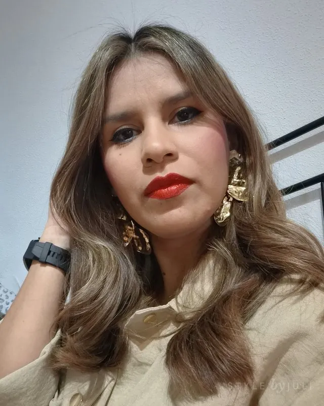 Juli con ondas beige, labios rojos y pendientes dorados